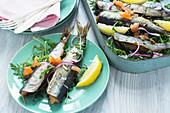 Oven-roasted young herring with lemon on a bed of rocket