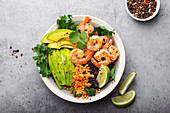 Salad bowl with shrimps, avocado, fresh kale, quinoa, red lentils, lime and olive oil