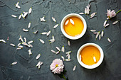 Grüner Tee in zwei Teebechern und Chrysanthemenblüten