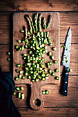 Sliced green asparagus with a knife on a wooden surface