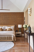 Console table and double bed in bedroom with bamboo wall