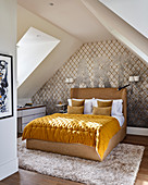 Yellow quilt on double bed in attic bedroom