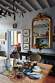 Antique mirror on blue wall and breakfast on table in dining room