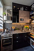 Gas cooker and black glossy cabinets in small masculine kitchen