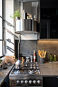 Runde Dunstabzugshaube überm Gasherd in kleiner Küche in Grau