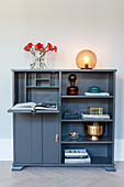 Dark grey sideboard with fold-down reading desk and ornaments in shelf compartments