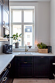 L-shaped fitted kitchen with black fronts and white worktops