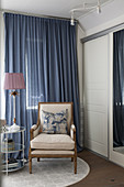 Classic armchair in front of blue curtain in bedroom