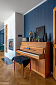 Piano and piano stool in open-plan interior with blue wall