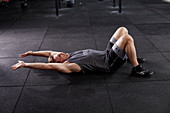 Junger Mann bei Fitnessübung Deck Squat