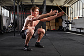 Junger Mann bei Fitnessübung Jumping Squats