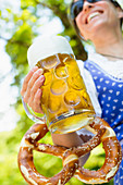 A woman holding a large beer and pretzel