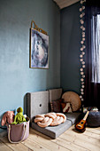 Folding mattresses and knotted cushion on wooden floor against blue wall