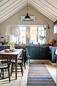 Blue cabinets and open roof structure in rustic kitchen-dining room