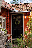 Wintry wreath on black front door of red Swedish house