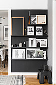 Pictures and books on ledges on black living room wall