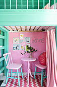 Two chairs and table against pink wall below loft level in play house