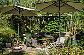 Shady spot below parasols on wooden terrace in summery garden