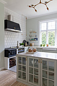 Glass-fronted cabinet in classic country-house kitchen with wood-fired cooker