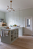 Glass-fronted cabinet in classic country-house kitchen with pale green walls