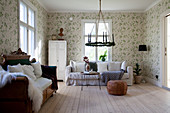 Loose-covered couch, antique wooden sofa and green-and-white floral wallpaper in eclectic interior