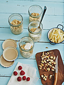 Overnight oats with yoghurt, fruit and nuts being made in glasses