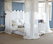 Blue walls and white four-poster bed in romantic bedroom
