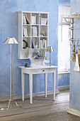 Console table below shelves mounted on pale blue wall