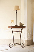 Side table with metal base in front of battered wall