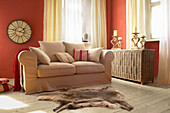 Beige sofa and wicker trunk in living room with red walls
