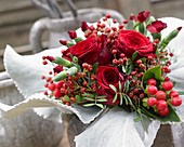 Strauß mit roten Rosen und Hagebutten in Manschette aus Senecio 'Angel Wings'