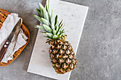 Fresh pineapple on a white marble platter on a stone surface