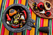 Roasted vegetables placed on black tray in colorful kitchen towel