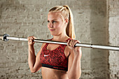 A young woman pressing a barbell without weights