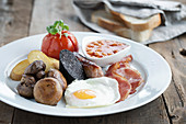 English Breakfast served on a white plate with white sliced bread in the background