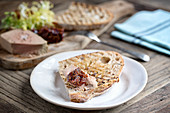 White plate with pate on toast, wooden board in background