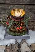 Pyramid arrangement of cypress, pine cones, dogwood wreath and brass bowl