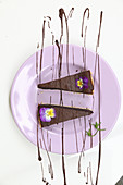 Two pieces of chocolate tart with horned violets
