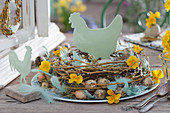 Easter wreath of willow branches, quail eggs, onions, primrose flowers, feathers, chicken and rooster