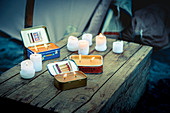 Candles in tin cans and candle ends on top of wooden crate