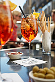 Aperol Spritz, olives, almonds and grissini in a restaurant