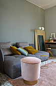 Graues Longseat-Sofa davor rosa Samthocker mit Messingfuß