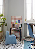 Blue felt chair at vintage school desk against patterned wall panel