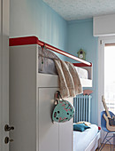 White bunk beds with wardrobe element in siblings' bedroom with light blue walls
