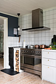 Large cooker with oven, firewood store and wood-burning stove in kitchen with white wall tiles
