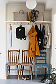 Jackets and bags hung from coat rack above row of chairs
