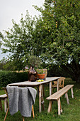Gartentisch mit Sitzbänken und Rattanstühlen im Garten