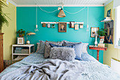 Schlafzimmer im nostalgischen Flair mit Bett vor türkisfarbener Wand