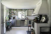 Old, decorative wood-burning stove and modern stainless steel cabinets in white kitchen