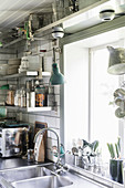 Offene Edelstahlregale für Küchenzubehör daneben Edelstahlspüle vor Küchenfenster